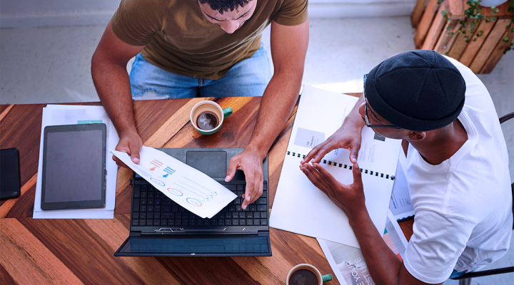Mid Size Business Owners Drinking Coffee and Discussing Marketing Challenges at a Table Crunching Numbers