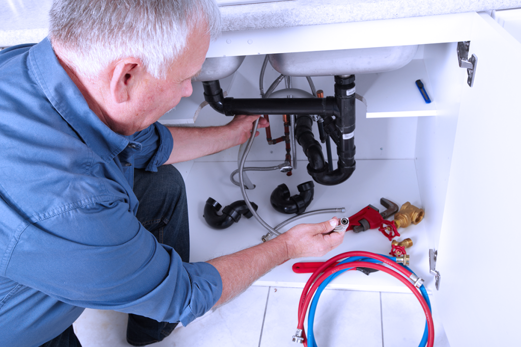 Plumber Working Under a Sink Fixing Water Supply Lines