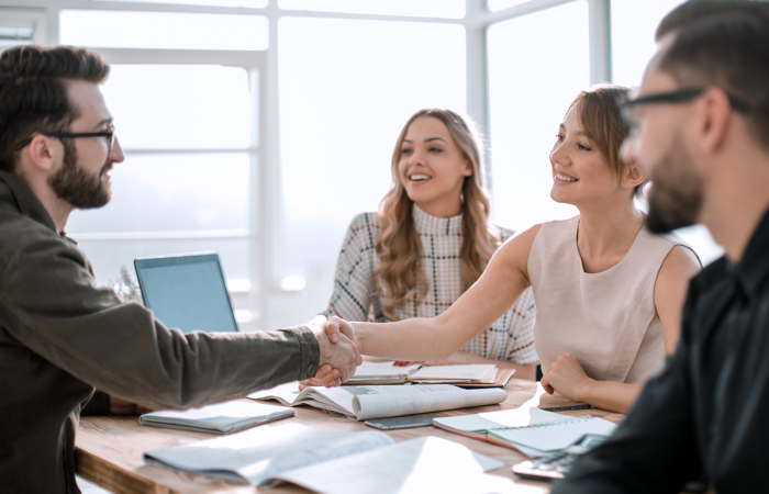 Small Business Sales Team Discussing Strategy with a Client Shaking Hands